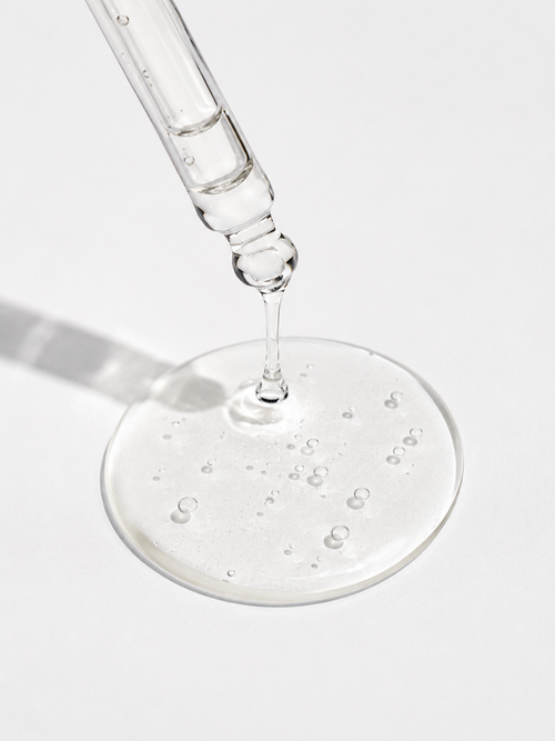 Close-up of AHA exfoliating serum texture with glossy gel and micro bubbles representing gentle chemical exfoliation and skin renewal.