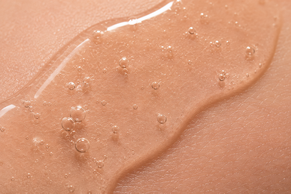 Close-up of AHA exfoliating serum texture with glossy gel and micro bubbles representing gentle chemical exfoliation and skin renewal.